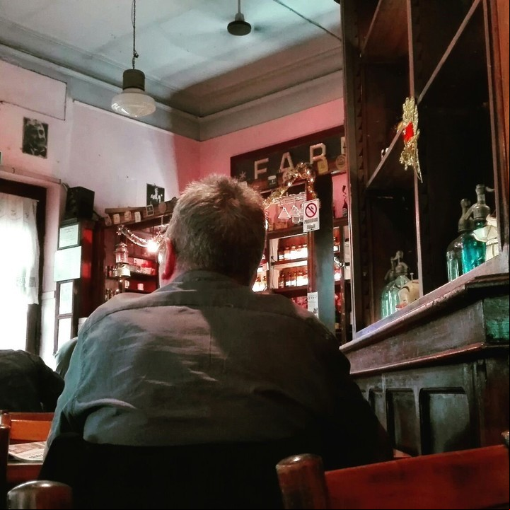 Aira en La Farmacia. El escritor, esquivo a los flashes, en el bar de Flores donde va a escribir./ Gentileza Roberto D'Anna