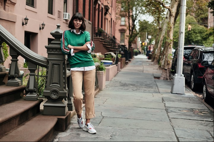 Suéter verde con tira insigne roja, blanca y azul en las mangas, camisa blanca y pantalones chinos.