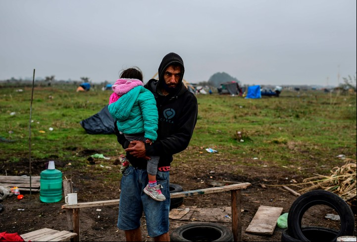 Un hombre con un niño en brazos en la toma de Guernica, en provincia de Buenos Aires. Foto AFP