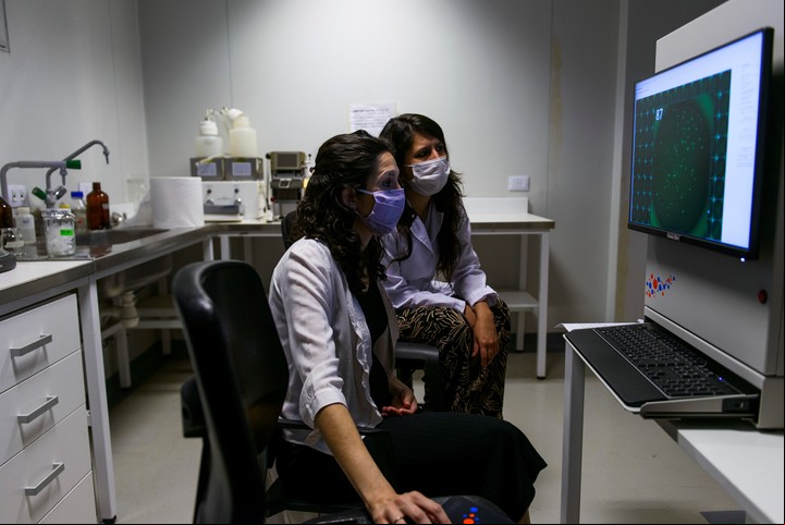 Eliana Castro y Lorena Coria, especializadas en diseño de vacunas, observan un recuento de células infectadas. Foto: Andrés D'Elía.