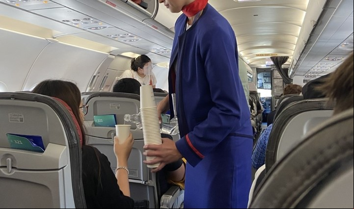 Una azafata les sirve agua a los pasajeros durante la espera a bordo.