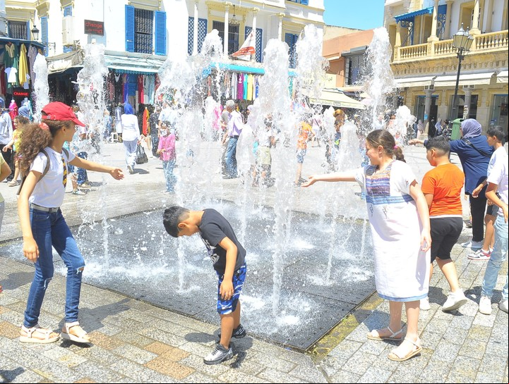 Niños combaten el calor con el agua de una fuente. Foto Xinhua