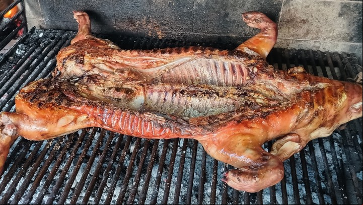 El lechón a la parrilla se cocina con el cuero para arriba y se da vuelta para dorarlo al final de la cocción.
