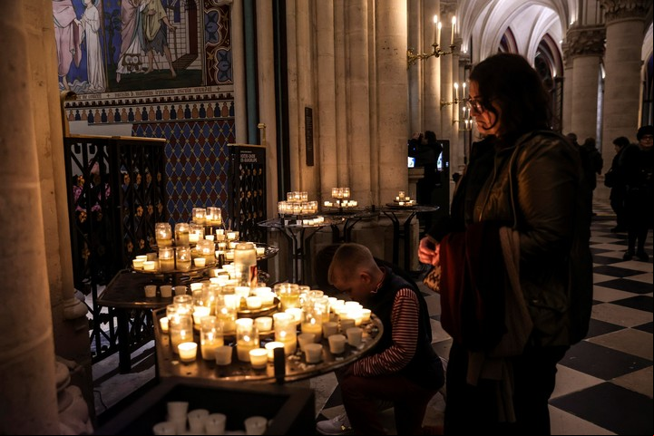 Una mujer y un niño encienden velas en Notre Dame. Foto: EFE