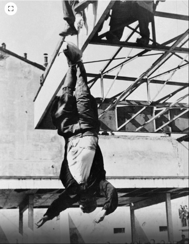 Los partisanos comunistas izan el cuerpo sin vida de Benito Mussolini en la estación de servicio de Milán (AP)
