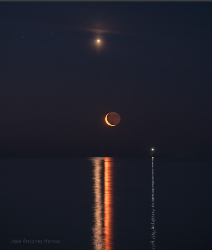 La Luna poniente, Venus (arriba) y Saturno (derecha, débil). El otro objeto brillante con una línea reflejada en el agua es una baliza en una roca para advertir a los barcos que pasan (José Antonio Hervás - NASA).