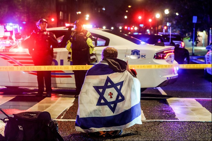 Un hombre con una bandera israelí cerca del lugar donde fueron asesinadas a tiros dos empleados de la embajada. Foto: EFE